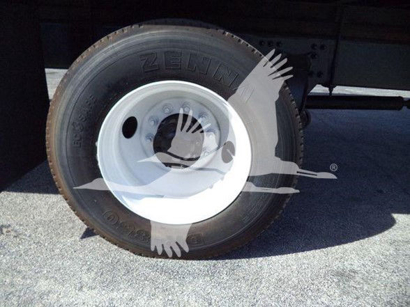 Truck wheel with white rim and tire labeled ZEIN; visible portion of truck undercarriage.