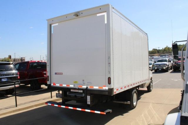 Box truck rear three-quarter view showing cargo box with reflective tape and rear bumper. Ford E-450 blank white box, VIN plate area not visible.