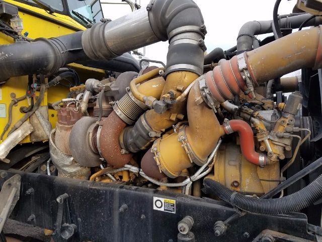 Engine bay of a 2009 Peterbilt 389 with multiple curved turbo pipes and yellow-orange engine components.
