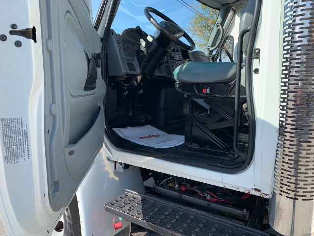 Driver's seat area of a 2006 International 4300 garbage truck cab showing steering wheel, dash, and entry step.
