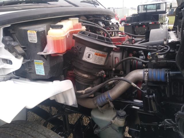 Freightliner M2 engine bay showing coolant reservoir, air intake, hoses, and various service stickers.