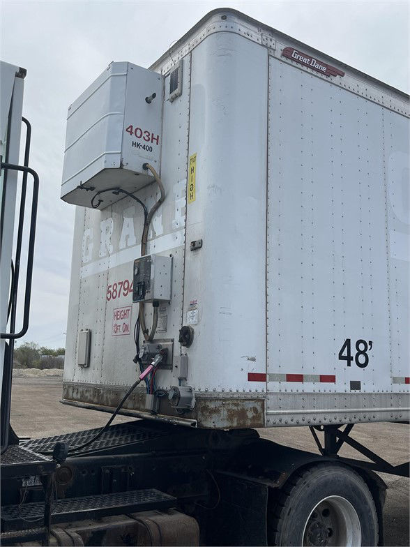 Great Dane dry van trailer with auxiliary cooling unit mounted on front left side, 48' length marking, stock number stickers, and rear undercarriage visible.