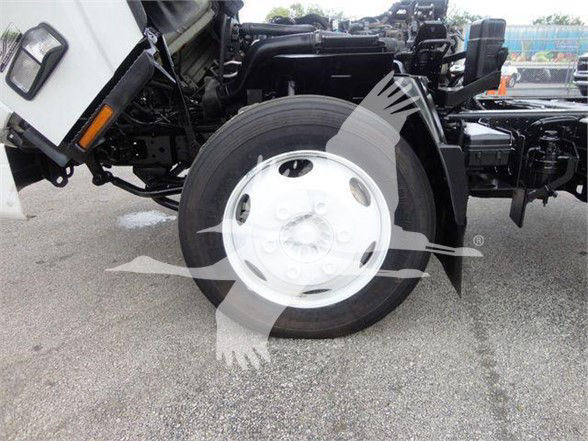Isuzu truck front wheel and chassis showing wheel with white rim and tire, partial cab and frame visible.