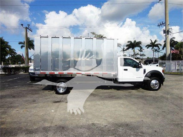 Dumpster truck body on a white 2022 Ford F550 dump truck side view with chrome wheels and aluminum dump box.