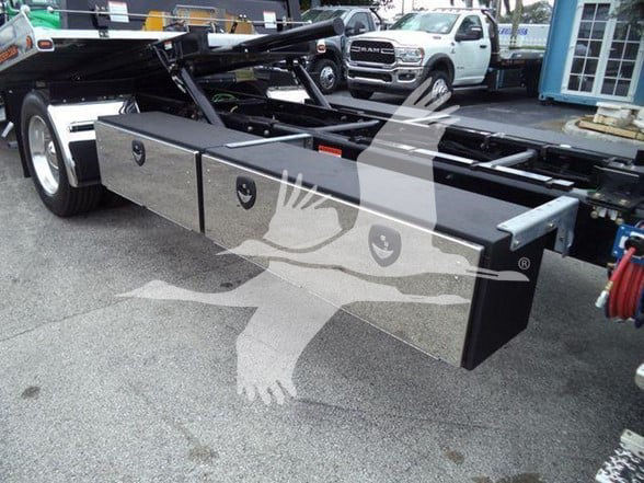 Freightliner M2 106 chassis showing three rectangular aluminum tool/storage boxes mounted under the cab with latching handles.