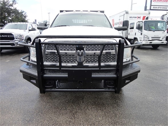 Front view of a white 2012 Ram 3500 SLT with heavy-duty grille guard and bumper guard in a parking lot.