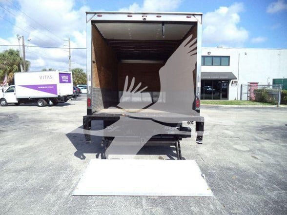Isuzu NRR box truck with liftgate raised, empty cargo area visible; back doors open, ramp deployed on asphalt lot.