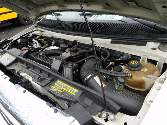 Ford E-450 engine bay showing coolant reservoir, power steering fluid cap, and air intake with battery visible under hood.