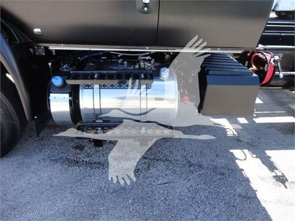 Truck side view showing cylindrical fuel or aftertreatment tank and adjacent equipment under the cab area.