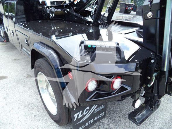 Front corner of a black 2025 International MV tow truck showing light bar and bumper with TLC logo and stock number plate.