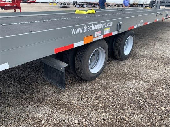 Container delivery trailer with tandem axles showing thecheaindrive.com decal and tire side, with mudflaps and reflective tape.
