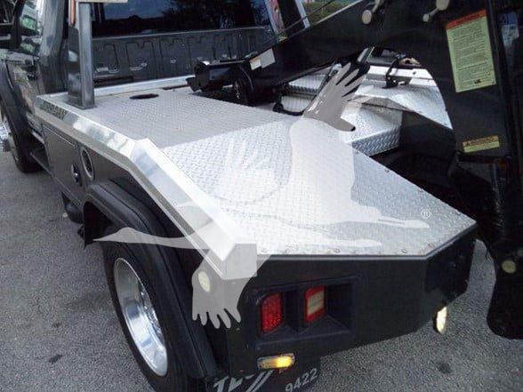Ford F-450 tow truck rear side bed with diamond plate aluminum surface and hydraulic wheel lift.