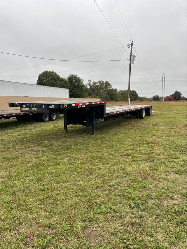  Fontaine 48x102 step deck trailer showing long flatbed with black frame and landing gear, reflective tape along sides, and tandem axles at rear.