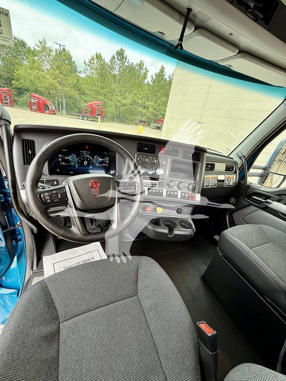 Kenworth T880 interior cab view showing steering wheel, dashboard, center control panel, and driver's seat in a new truck.