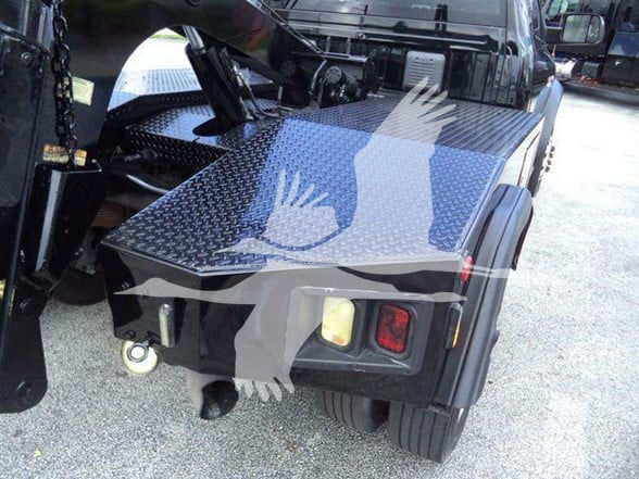 Truck hitch area with diamond plate platform and dual rectangular lights; front of wheel well visible; some hardware and a winch mount visible.