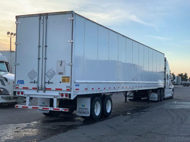 2017 Stoughton dry van trailer showing rear doors, dual rear axles, and a white cab behind. Exterior panels are smooth with small safety stickers and reflectors along the lower edge.