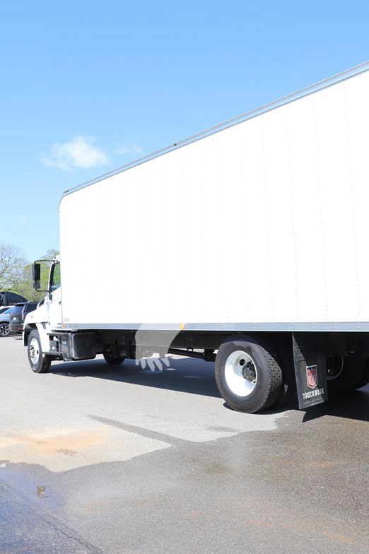Truck cab and box from a side angle showing a white box trailer and front cab, rear wheels visible.