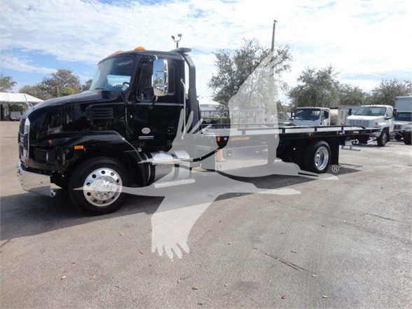 A black 2025 Mack MD6 tow truck with a lift flatbed is parked outdoors. Visible text includes 'MACK MD6' on the cab and license/stock may not be legible.