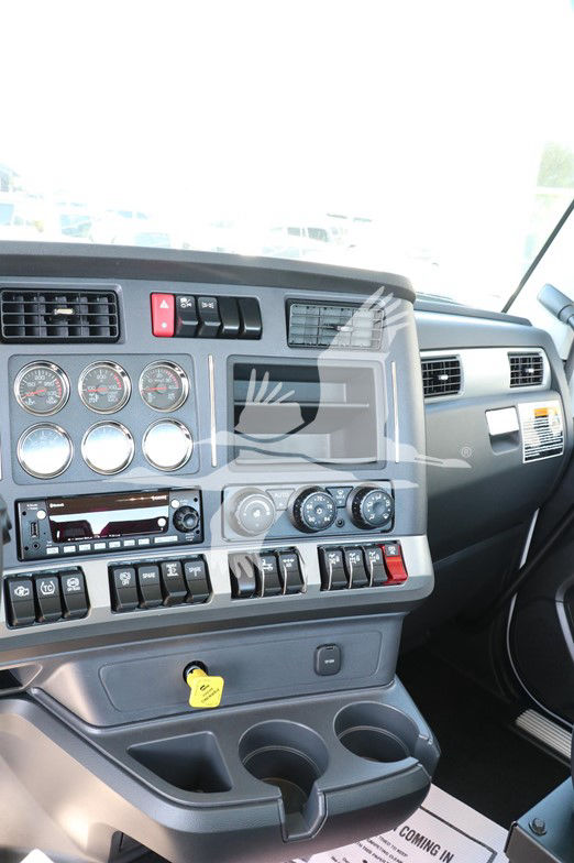 Kenworth T880 cab interior dashboard with multiple gauges, switches, vents, and a cup holder area. Visible text includes various dials and labels on switches.
