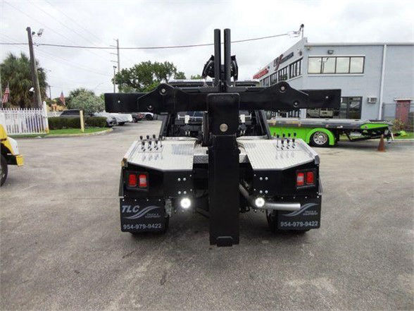 Tow truck rear with hydraulic apparatus and dual platform; visible lights and control hardware.
