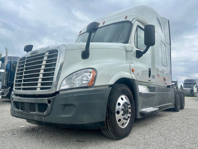 Truck front-left view of a white Freightliner Cascadia 125 sleeper tractor. Dashboard and windshield area visible with side mirrors.