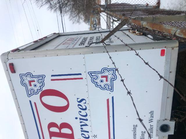Truck box side with B O I services logo and barbed wire fence in foreground.