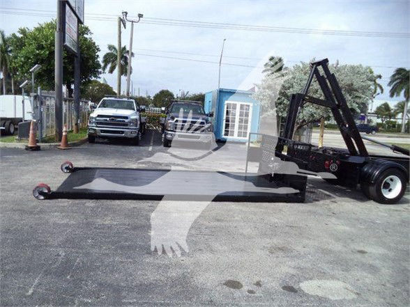 2017 Hino 258LP hooklift truck chassis with a lowered flatbed and hooklift apparatus in a used vehicle lot.