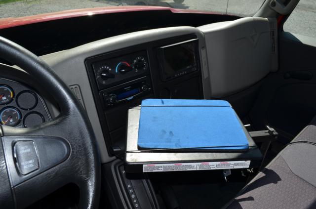 Dashboard and center console of a 2013 International TerraStar cab with a blue portable device case on the center console.