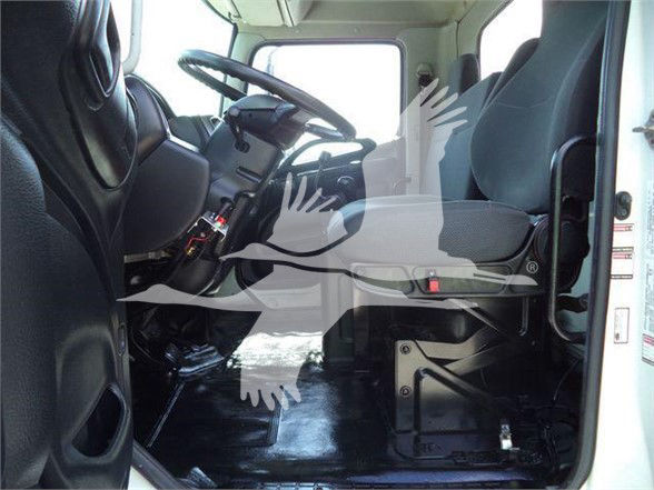 Cab interior of a 2016 Hino 268A dump truck showing driver seat, steering wheel, and dashboard from the doorway.