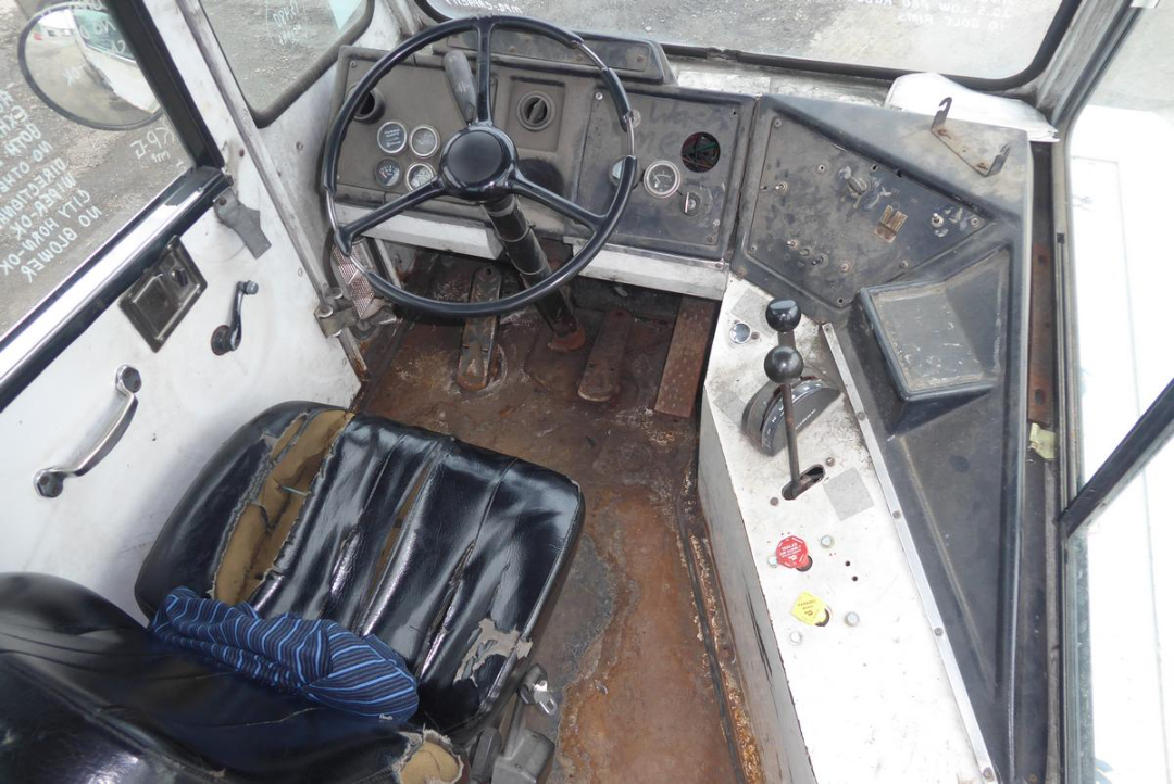 Cab interior of a used Capacity TJ5000 truck showing steering wheel, dashboard with gauges, gear lever, pedals, and a worn seat.