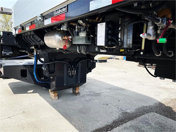 Trailer undercarriage with hydraulic components, hoses, and metallic frame showing Goldhofer branding and mechanical systems.