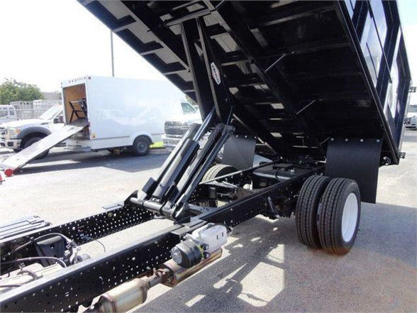 Isuzu NPR HD dump truck chassis with raised dump bed showing hydraulic lift cylinders and dual rear wheels.