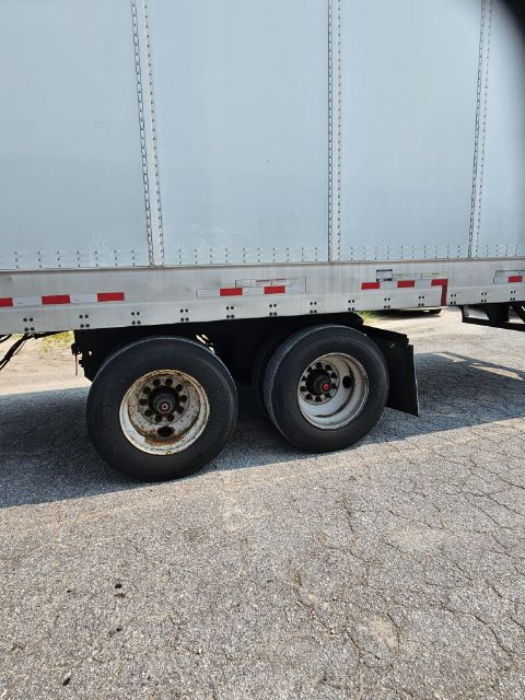 Dual rear wheels of a trailer with white sidewall and red safety stripes; visible are wheel rims and rubber tires; part of a box trailer body.
