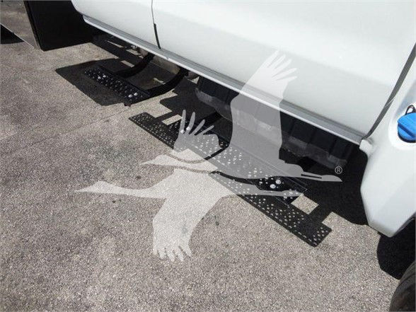 Step and side of a white dump truck with black metal steps under the cab and a blue fuel cap visible.