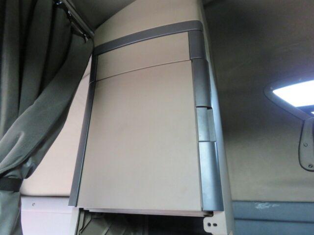 cab interior showing a light beige storage cabinet with dark gray trim in a Freightliner Cascadia Evolution truck.