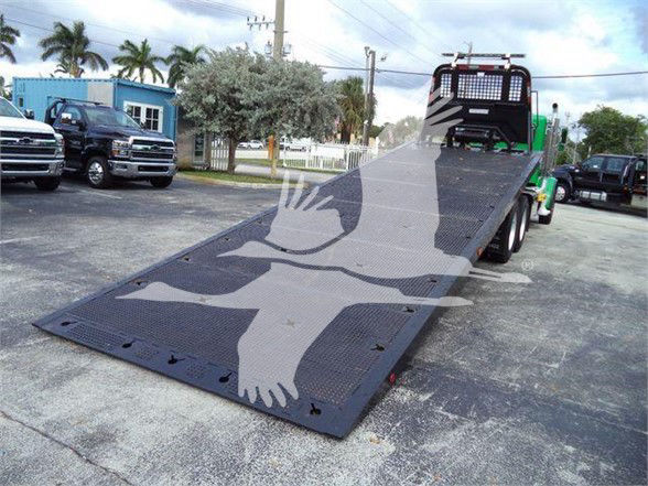 2014 Peterbilt 367 with a flatbed/dolly-style towing bed, rear view shows ramped platform and wheel setup; branding not legible.