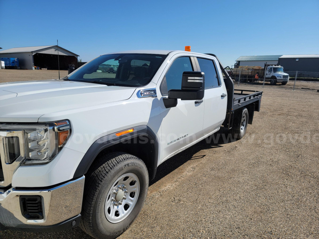 2020 GMC Sierra 3500HD flatbed truck in white, front-left angle showing crew cab, dual rear wheels, and flatbed.