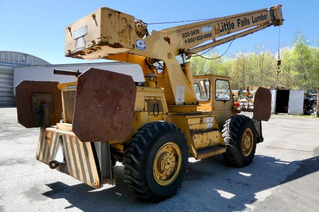 1969 Grove RT58 truck crane showing large yellow boom with rusted blocks and heavy tires, equipment with Little Falls Lumber branding on boom, side view.