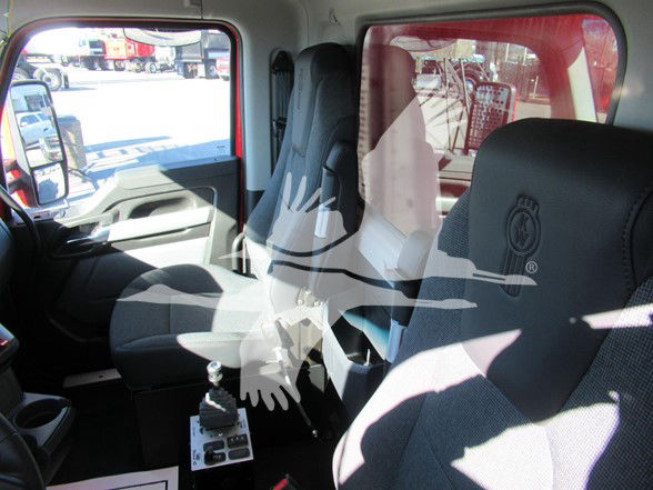 Interior of a new Kenworth T880 dump truck with captain chairs, driver and passenger seats, center console, gear shifter, and control panel visible. The image shows branding watermark across seats.