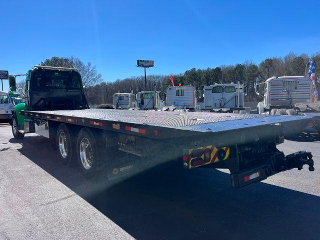 Peterbilt 348 rollback tow truck with flatbed, side view showing dual rear axles and gooseneck hitch area.