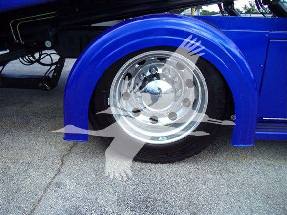 Truck wheel and blue fender of a 2024 Peterbilt 536, chrome hubcap, blue wheel arch.