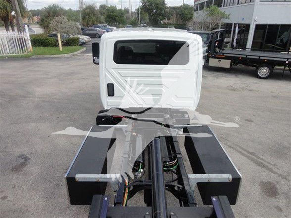 Tractor unit cab with chassis frame and hydraulic lines visible, rear view of white cab on a tow truck chassis.