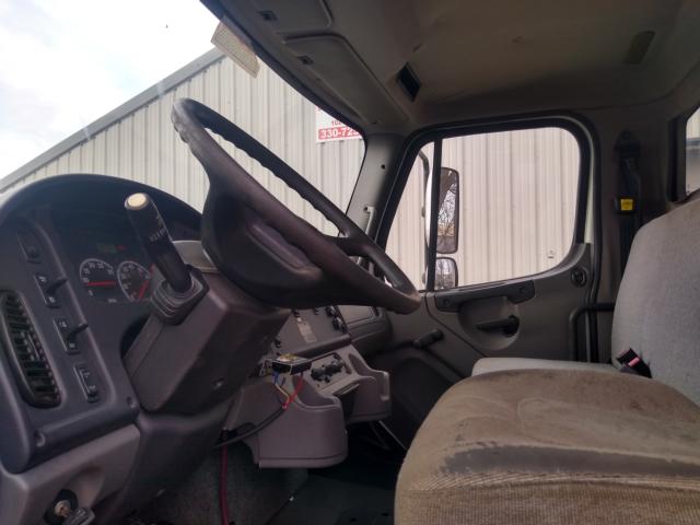 Cab interior of a 2013 Freightliner M2 with steering wheel, dashboard, and driver's seat visible.
