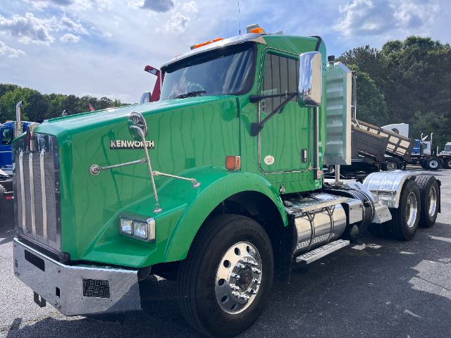 Green 2014 Kenworth T800 conventional daycab truck side view showing chrome exhaust stacks, large grille, dual rear axles, and dump trailer attachment.