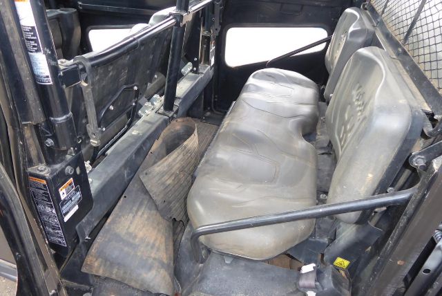 Kubota RTV-X1140 interior showing two seats with protective fabric, metal framework, and cargo area; dirty floor mat and side panels.