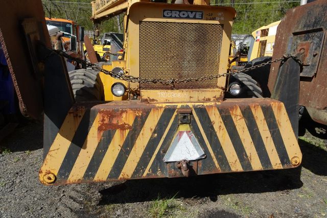 Front view of a yellow Grove RT58 crane truck showing striped bumper, chain safety lines, and headlights.