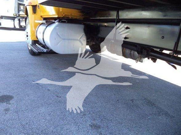 Underbody view of a yellow 2019 International DURASTAR 4300 with a large white fuel or hydraulic tank and chassis rails visible.