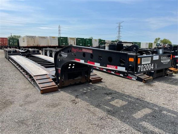 2020 Fontaine 55-ton tri-axle lowboy trailer with pony motor, black frame, long steel ramps on left, multiple wheel groups, white and red safety stripes, stock number 702004 visible.