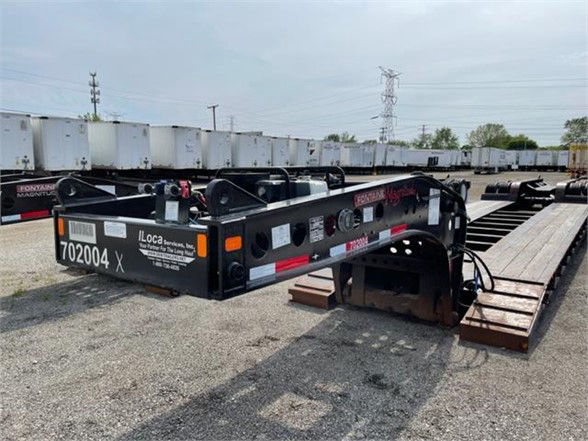 Tri-axle lowboy trailer with pony motor, black frame, 55-ton magnitude Fontaine layout, rear ramp sections extended, stock number 702004 visible.