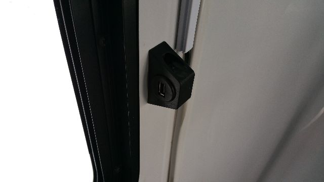 Door latch and edge of vehicle door on a 2009 Ford E-450 bus showing a black lockable latch on the door frame.